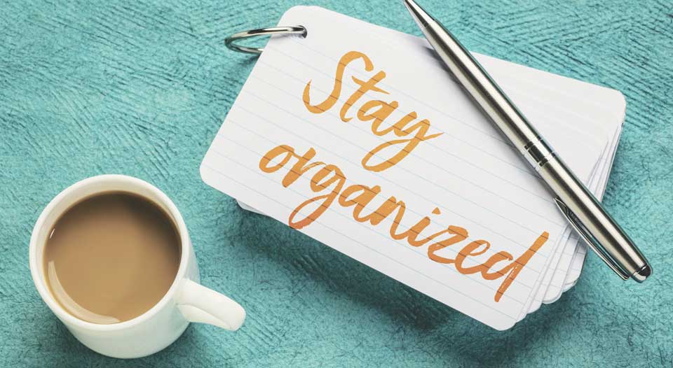 Coffee cup, pen and stay organized note on green table