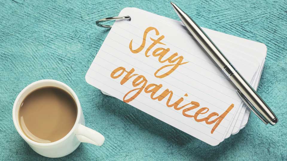 Coffee cup, pen and stay organized note on green table