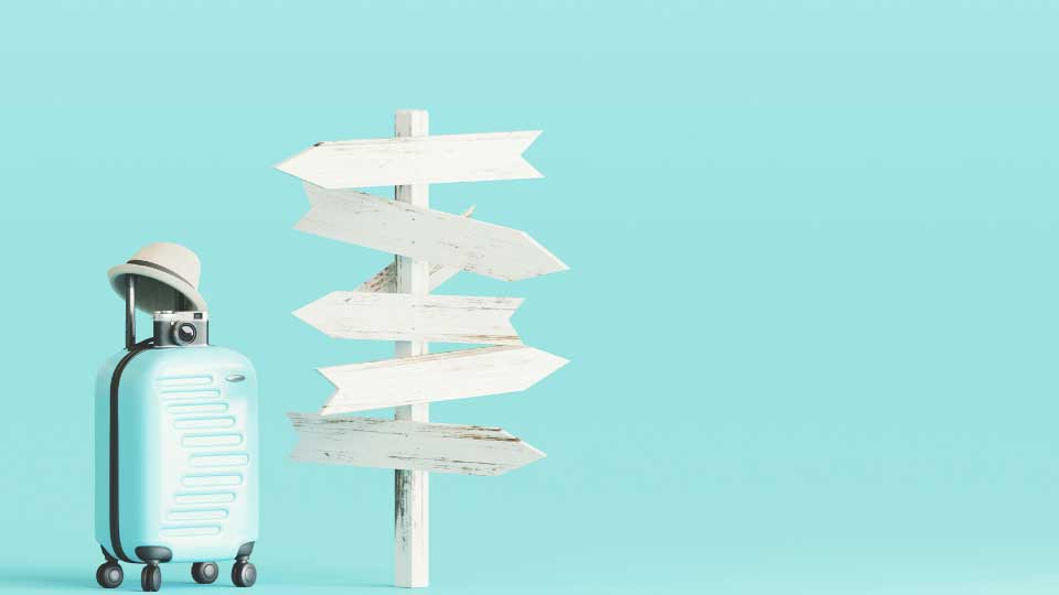 Blue suitcase and hat, camera with signpost on pastel blue background