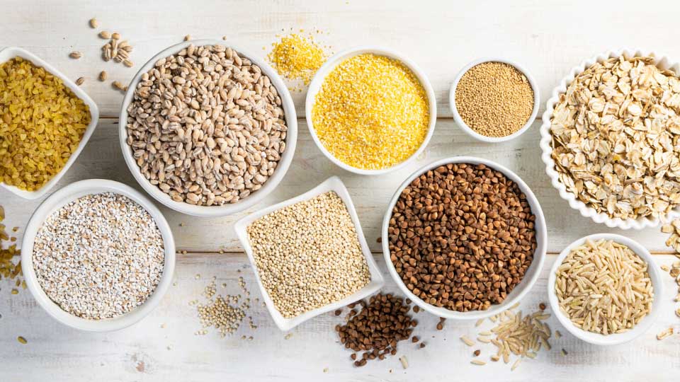 Different types of legumes and cereals on white background, top view. Organic grains