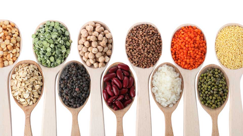 Selection of whole grains in white bowls - rice, oats, buckwheat, bulgur, porridge, barley, quinoa, amaranth, on white wood background