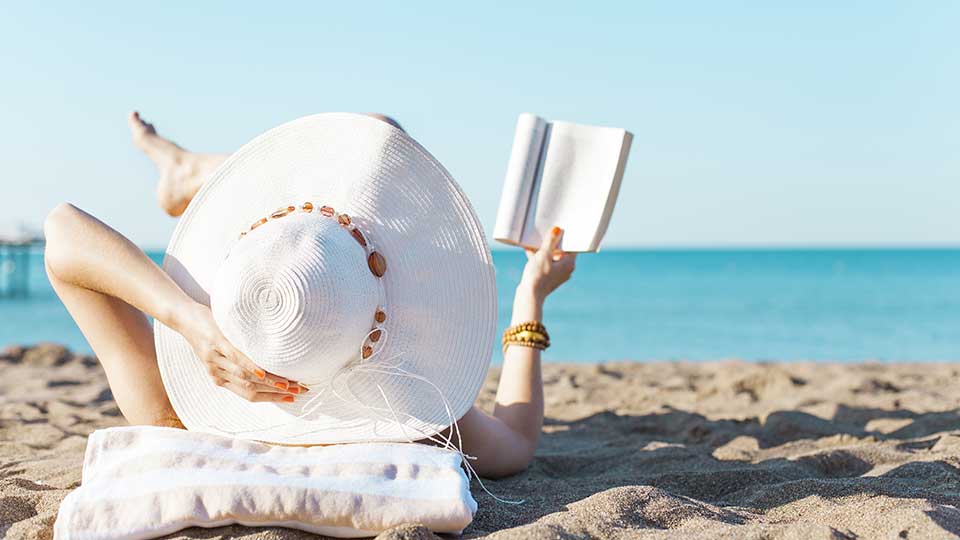 1. A person laying down on the beach reading