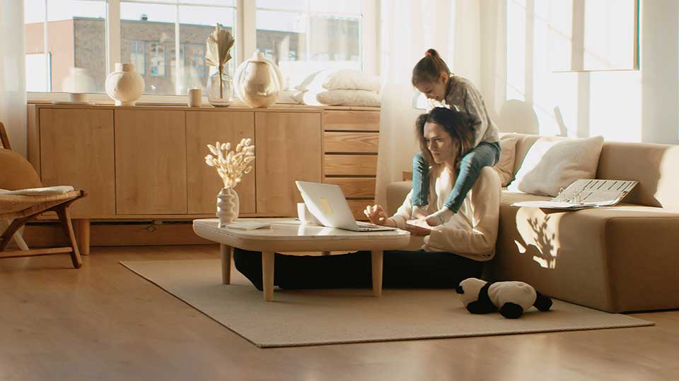 1. woman working on her laptop with child on her shoulders