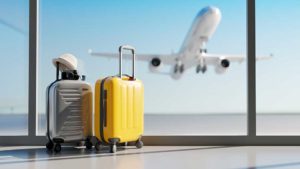 2 pieces of luggage in an airport with a plane taking off in the background