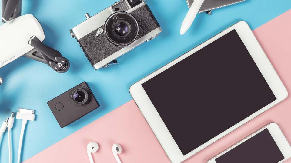 Travel gadgets flatlay on blue and pink background for travel concept