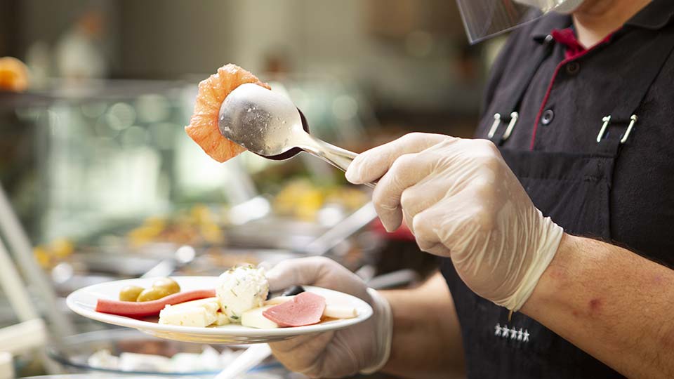 Chef with Covid 19 protective gear preparing individual plates