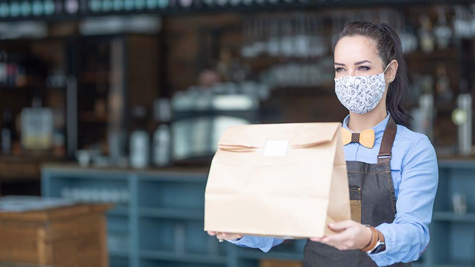 a waiter with Covid 19 protective gear handing out pre-packed meals